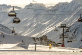 Viele verschiedene Skilifte führen über Skipisten, im Hintergrund sind verschneite Berge zu sehen, in Ischgl.