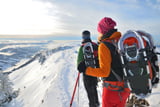 Zwei Schneeschuhwanderer sind in verschneiter Winterlandschaft am Berg unterwegs.