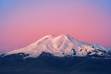 Der schneebedeckte Doppelgipfel des Elbrus im rosafarbenen Morgenlicht.
