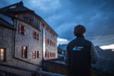 Das Watzmannhaus bei Nacht, im Vordergrund steht eine Person und schaut in den Sonnenuntergang.